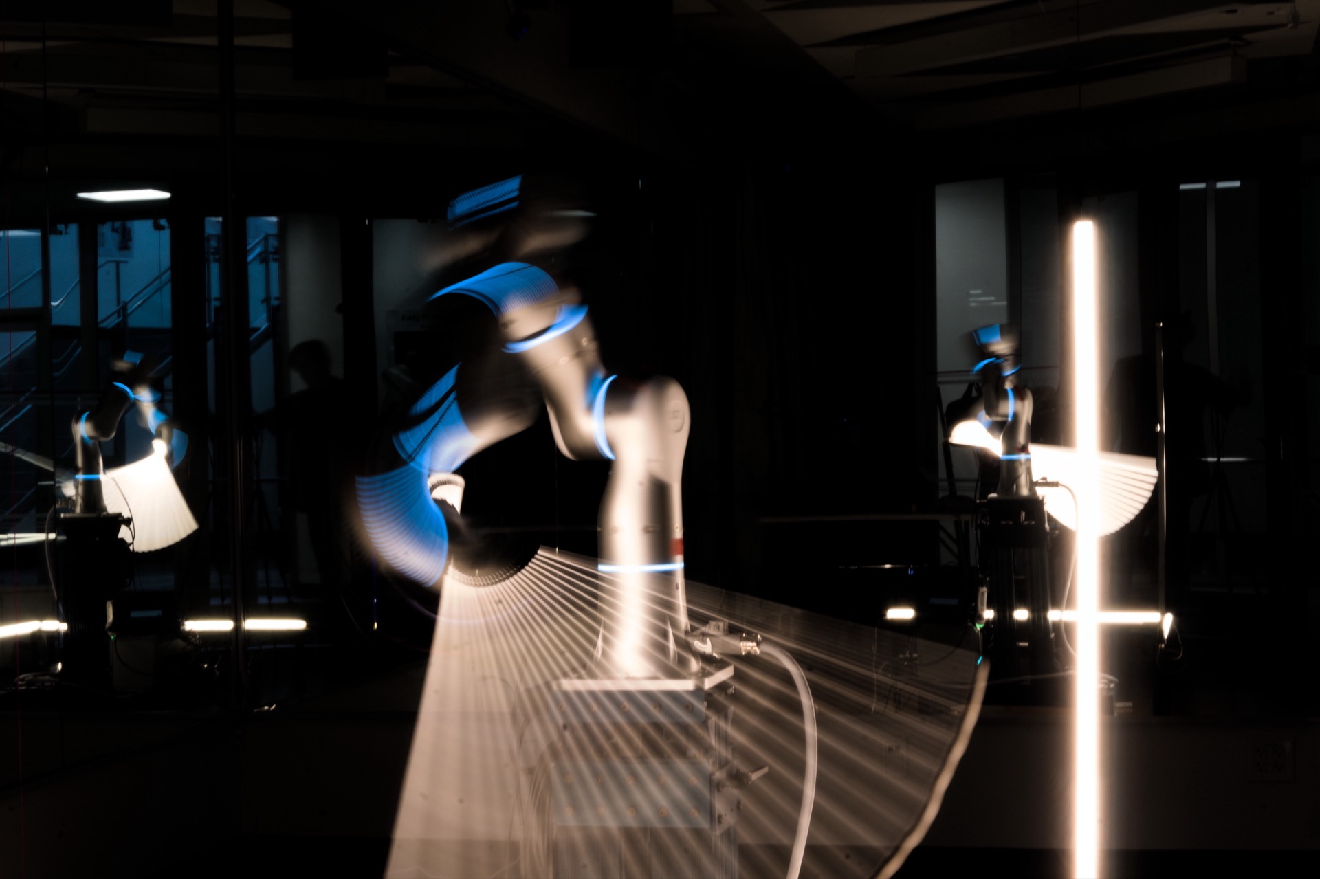 Motion-blurred close-up of the robot arm moving through a lit gesture