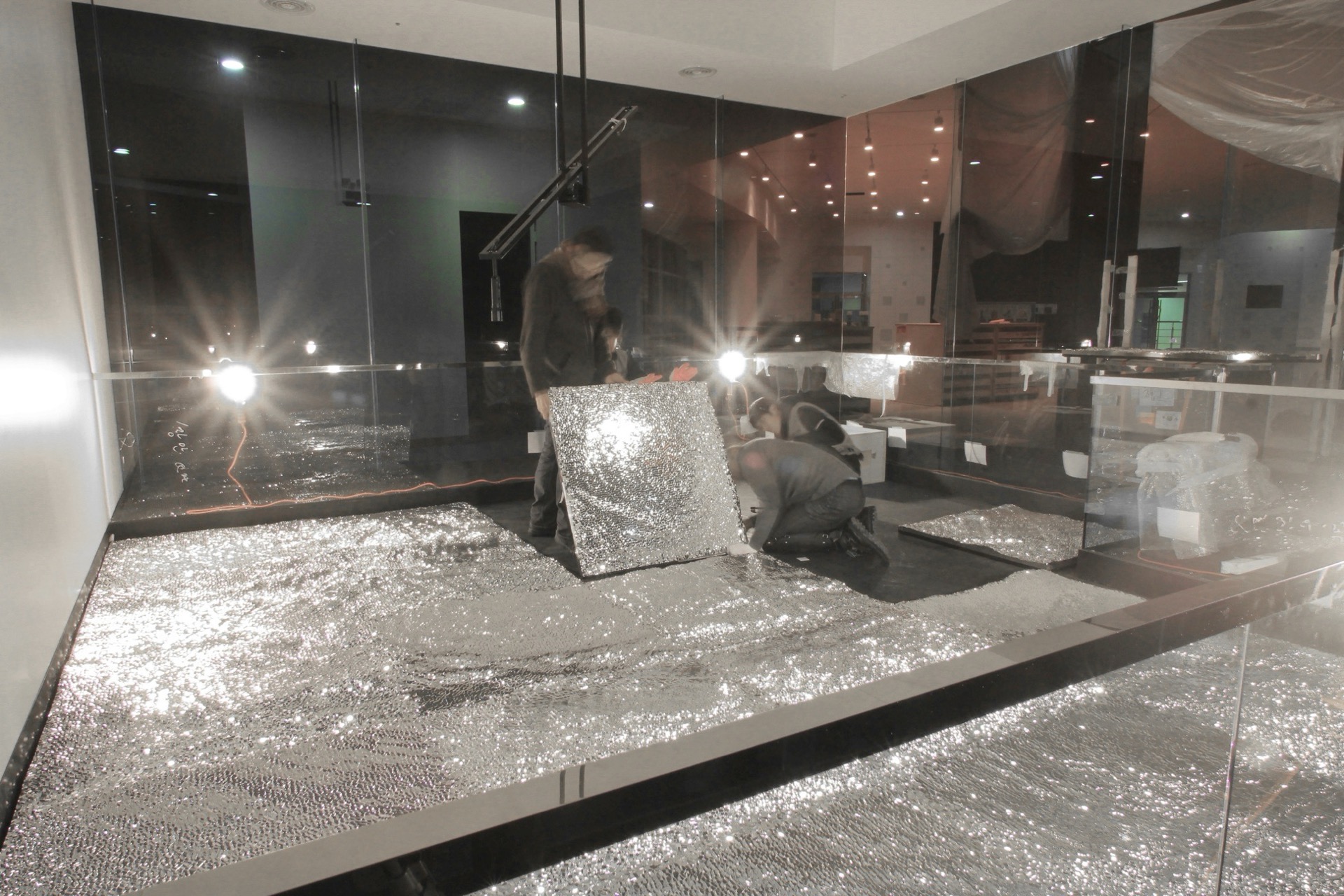 Full installation view showing the chrome sculpture and light projections